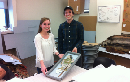 Seniors Tom Brown and Emily Dattilo, with one of the Indonesian shadow puppets in the collection.