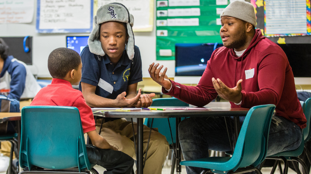 students and teachers sitting around a table talking