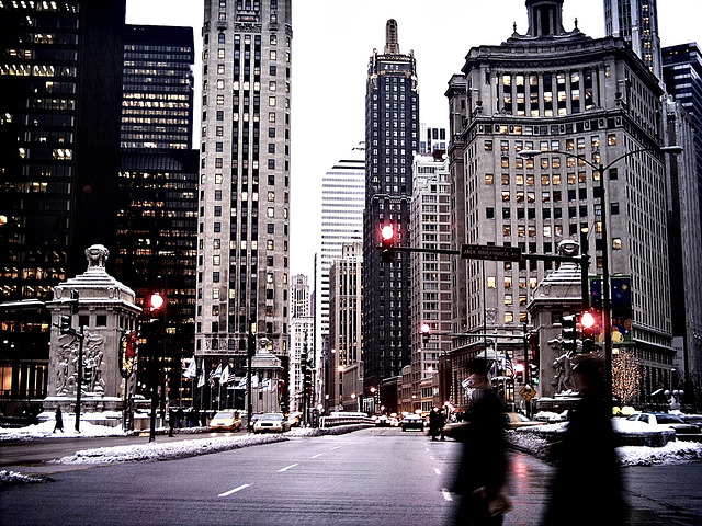 Downtown Chicago, looking north on Michigan Avenue, on a wet winter day. Two blurry figures cross the street in front of a red traffic light.