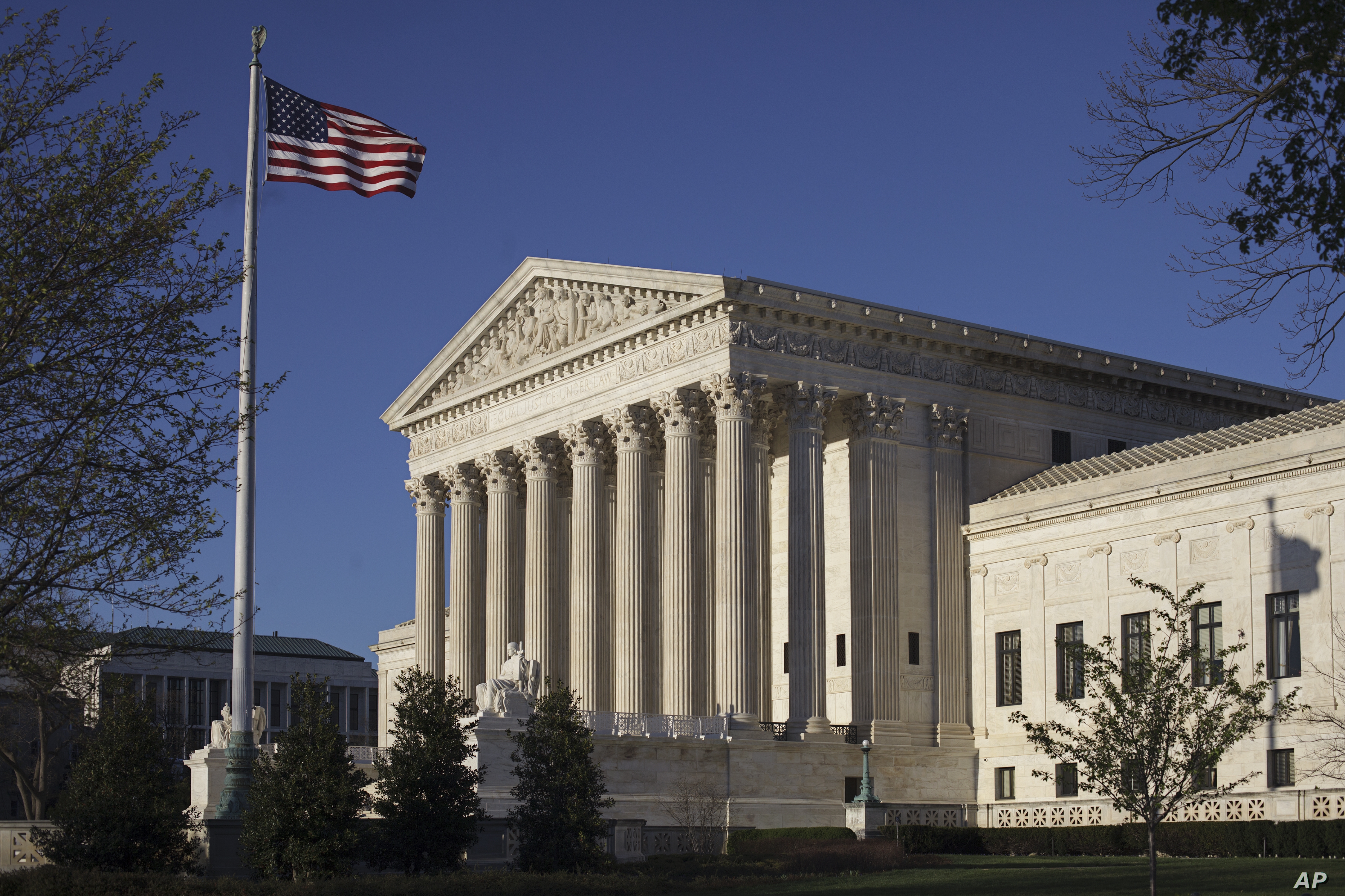 Supreme Court building with American flag flying next to it.