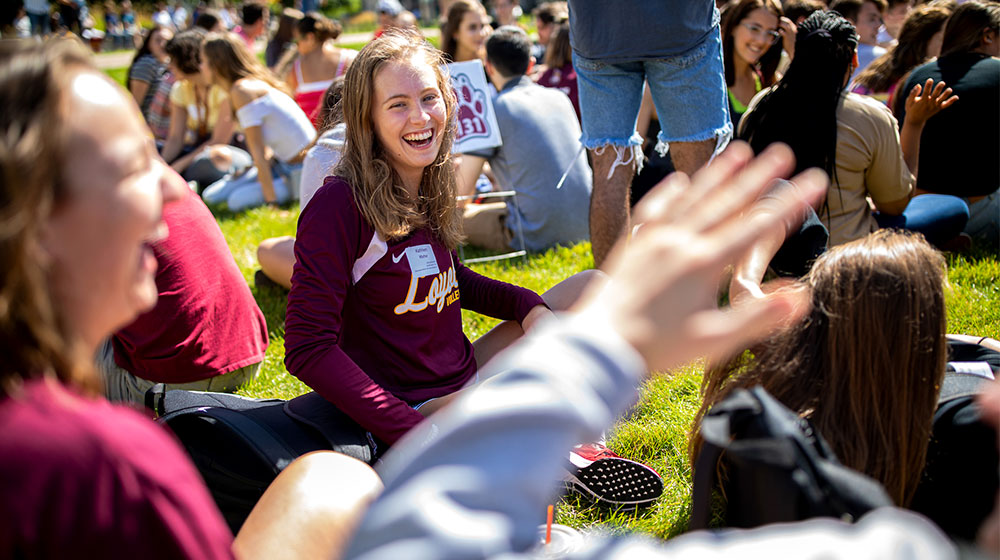 students sitting in grass during new student convocation