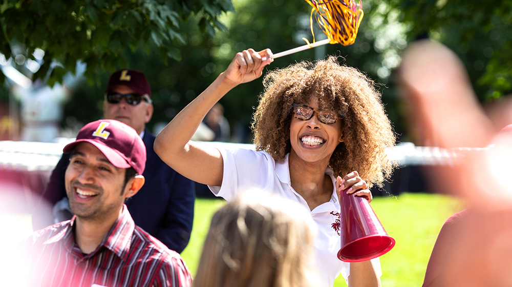 A student waving a maroon and gold pom-pom during new student convocation