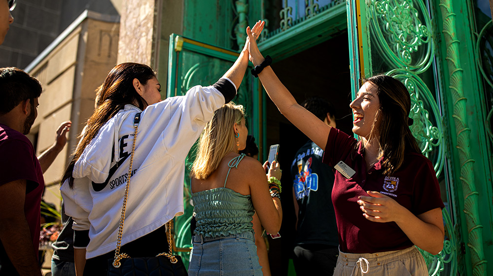 Two people high-five at the Loyola University Chicago new student convocation.