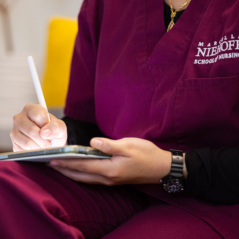 A close up of a nursing student writing on a digital tablet