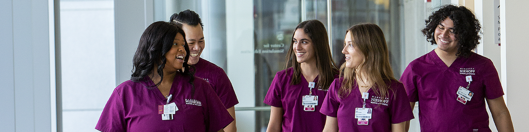 Loyola University Chicago students in maroon scrubs walk down the hallway 