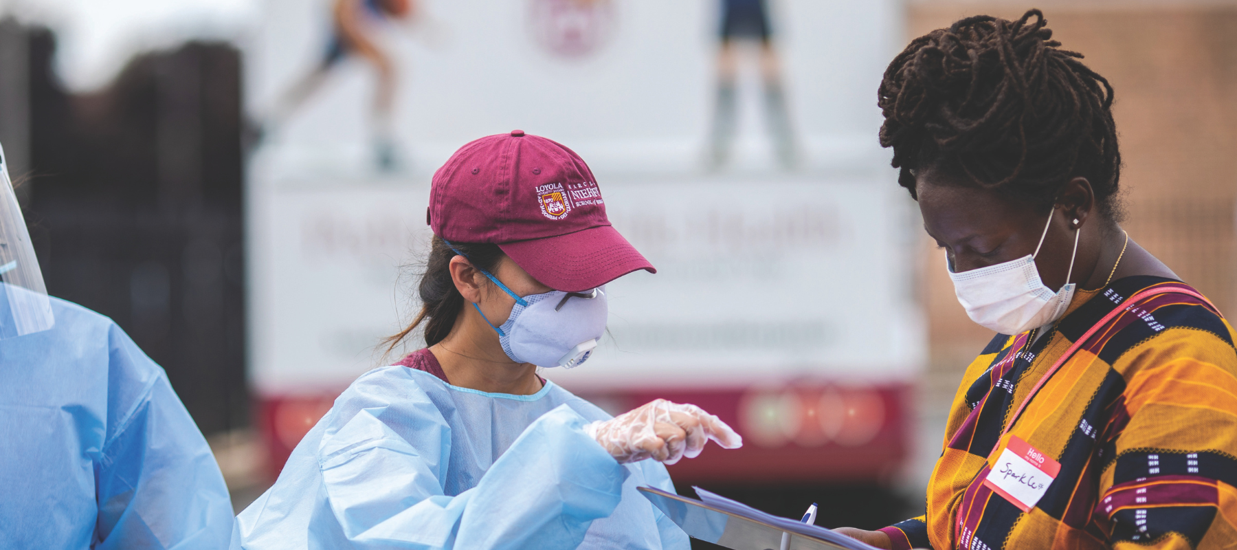 Two people wearing masks reviewing information on a clipboard.