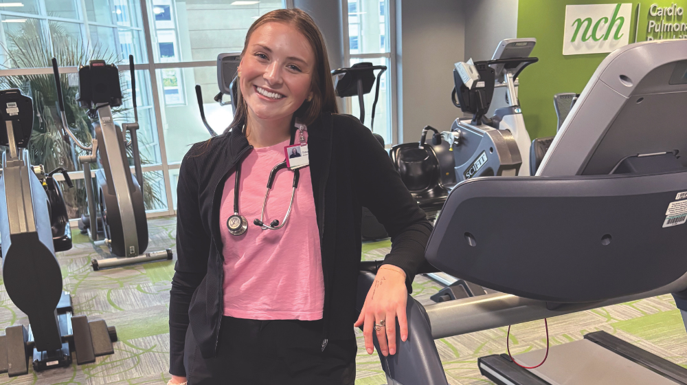 Woman leaning on the side of a treadmill and smiling for camera