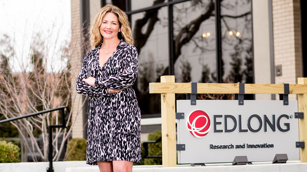 A woman in a black and white dress poses for a photo in front of a business sign that reads 