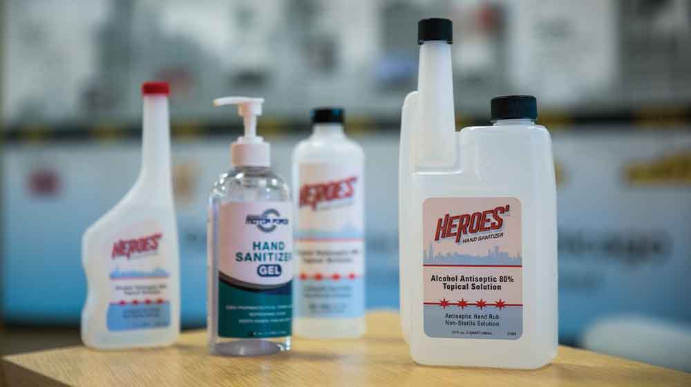 Four bottles of hand sanitizer on a table.