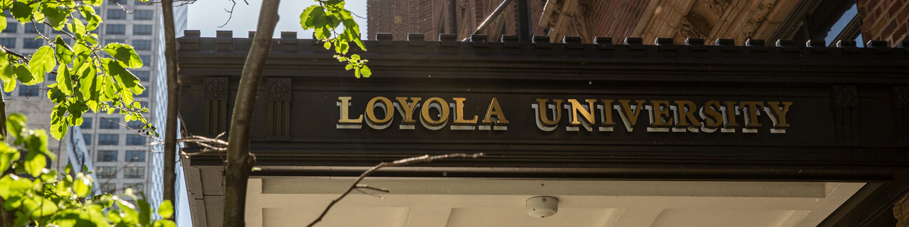 Lewis Towers building canopy reading Loyola University. There are skyscrapers in the background.