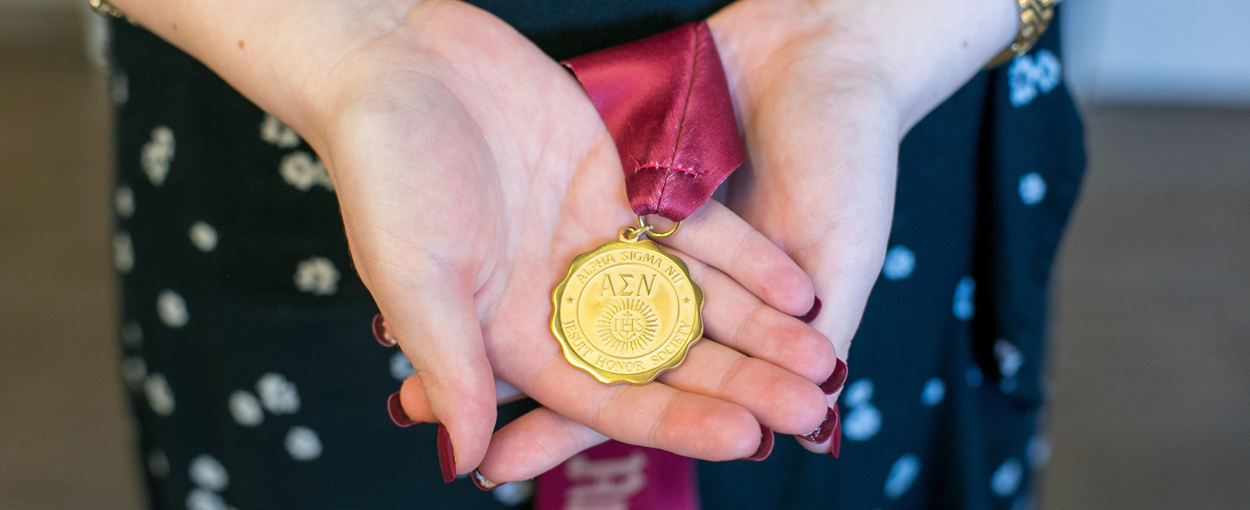 Loyola Chicago Alpha Sigma Nu Inductee holding medal in hand