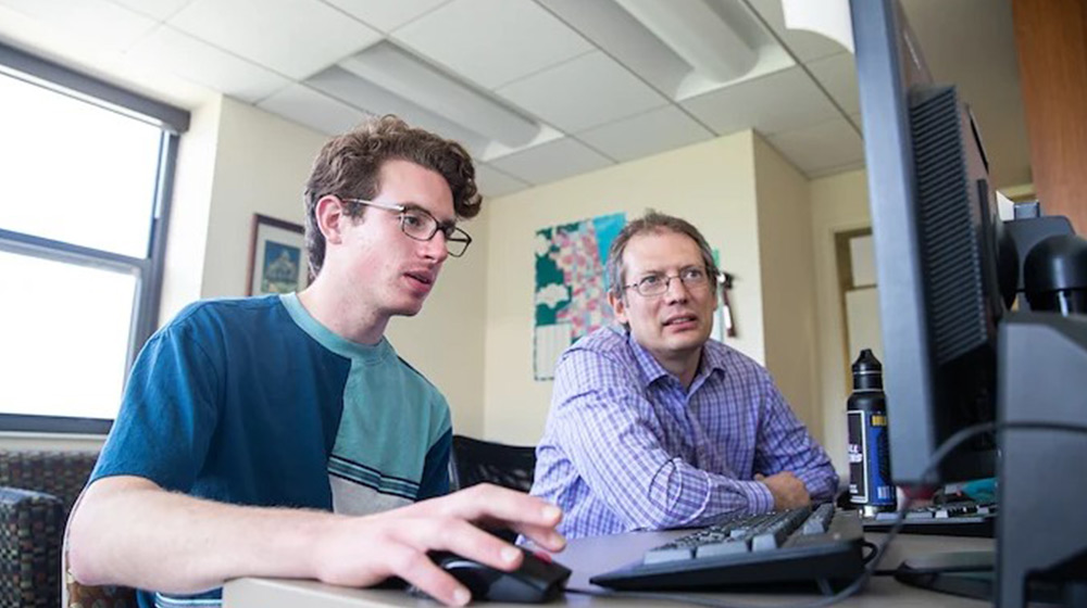 Undergrad Jonathan Nerenberg and Dr. Peter Rosenblatt analyze Chicago evictions at a computer