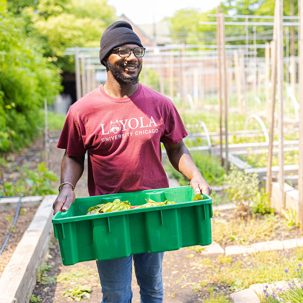 student carrying a bin of vegetables