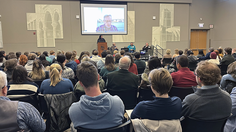 A large audience listens to Indigenous Peoples' Day speakers in Damen Student Center