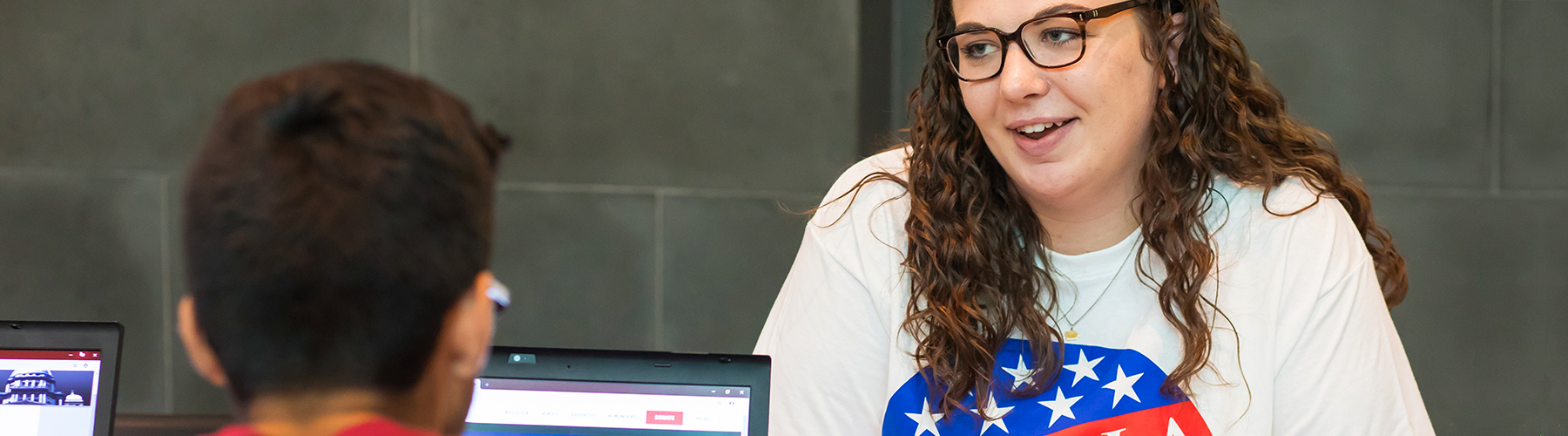 Loyola University Chicago graduate student Megan Jimmerson helps junior Wesley Heal register for an absentee ballot in the Damen Student Center on the Lake Shore Campus